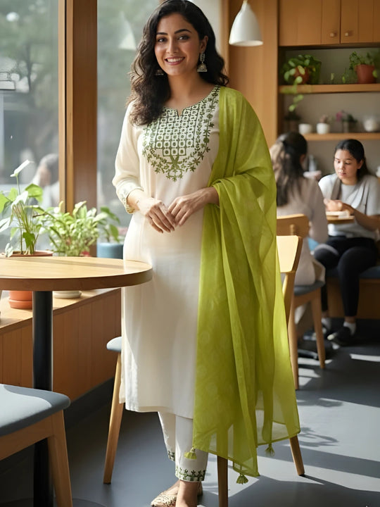 Woman in a white kurta with green dupatta standing in a modern cafe.