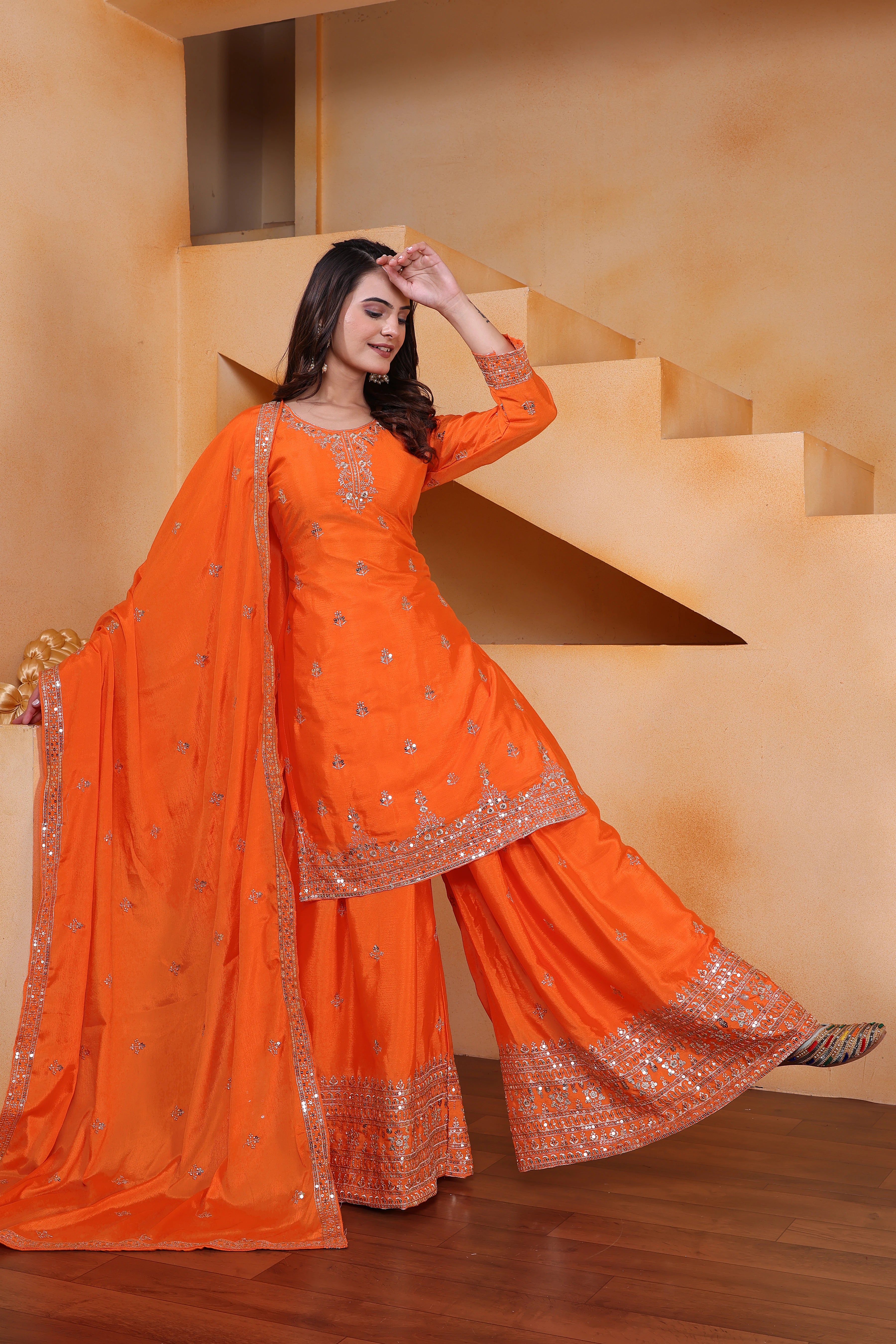 Woman in an orange traditional outfit standing on a staircase.