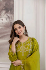 Woman wearing a green embroidered traditional outfit with a neutral background