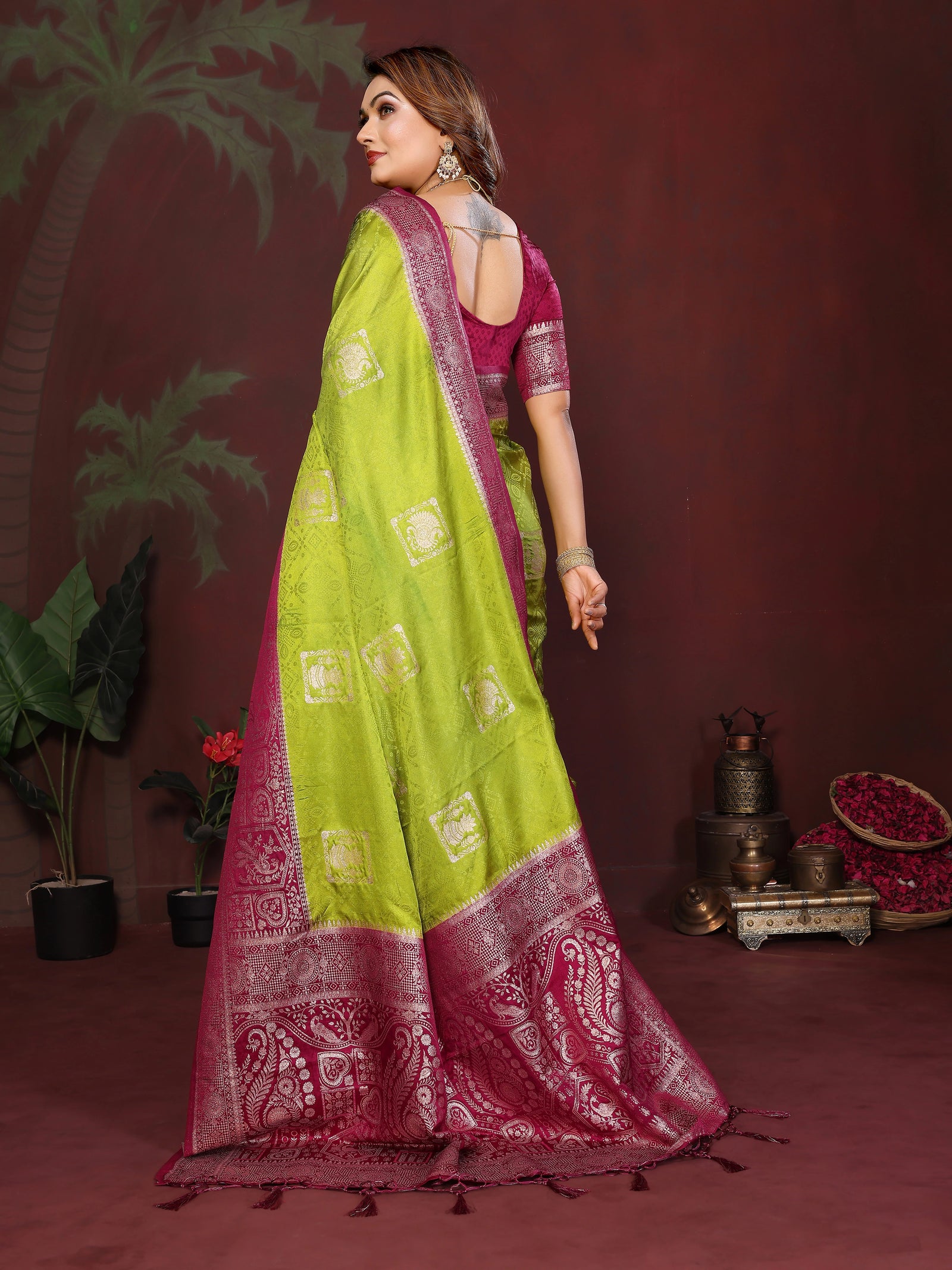 Woman wearing a green and pink saree with a dark background