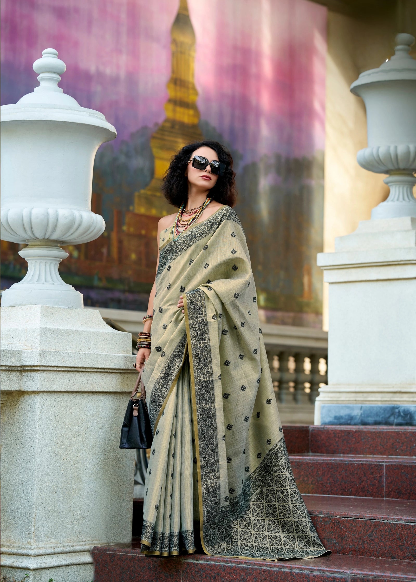Woman in a saree standing on steps with a colorful mural in the background