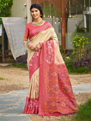 Woman wearing a pink and beige saree with floral patterns outdoors.