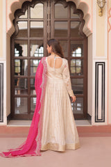 Woman in a white traditional outfit with a pink dupatta standing in front of an ornate door.