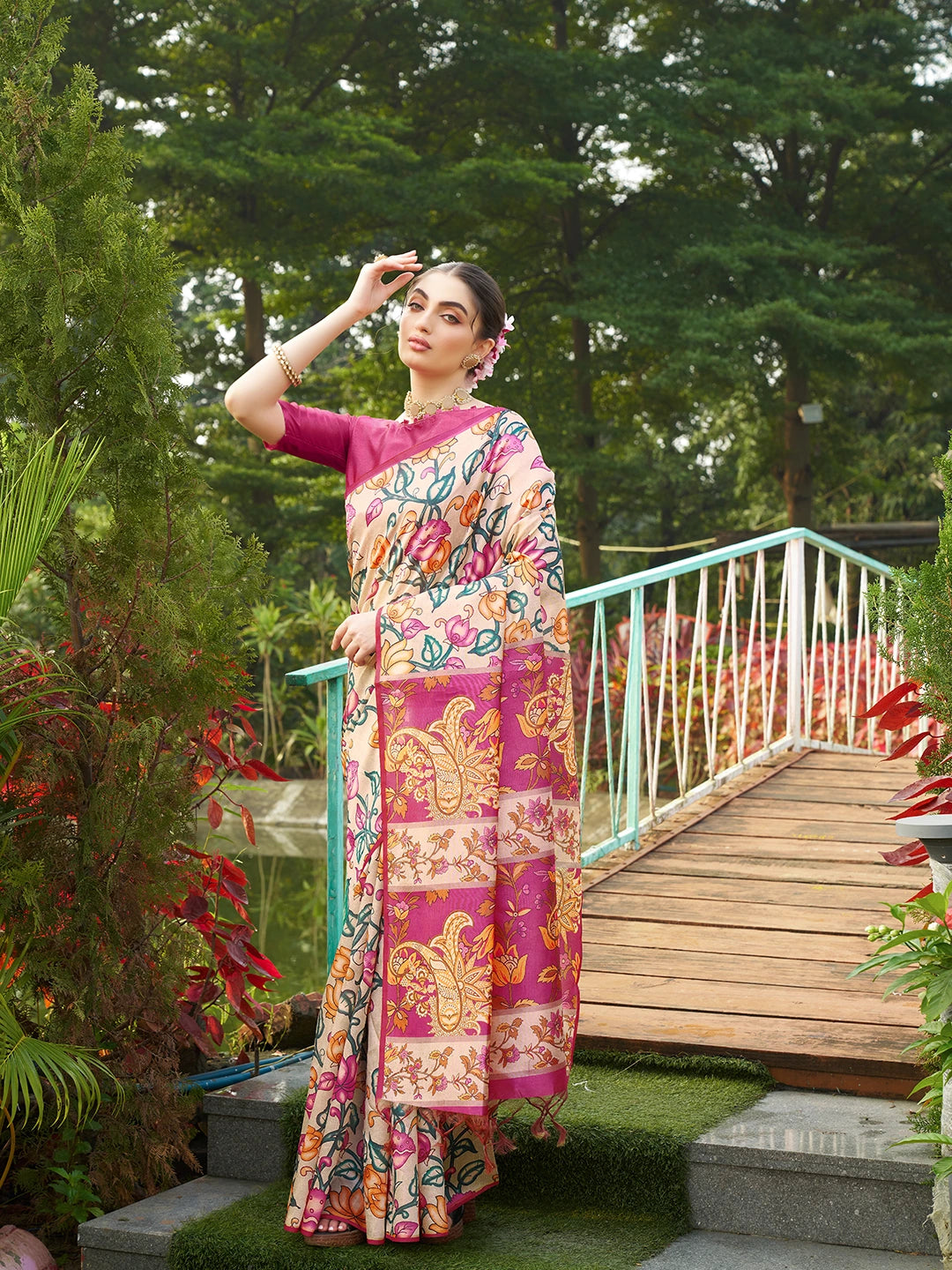 Women's beige floral saree with intricate magenta woven border and tassel pallu for festive occasions.