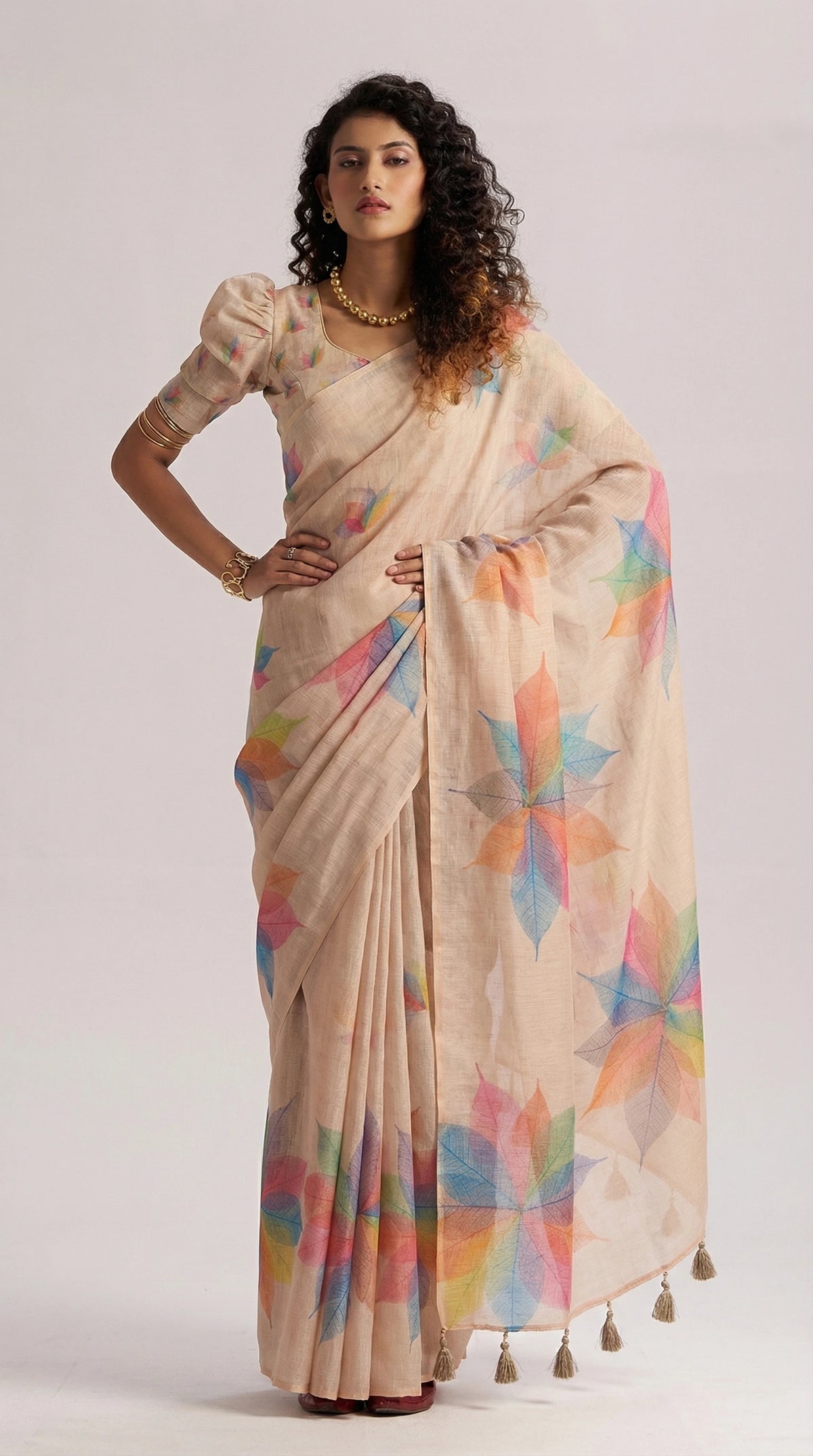 Woman wearing a beige saree with colorful patterns on a white background