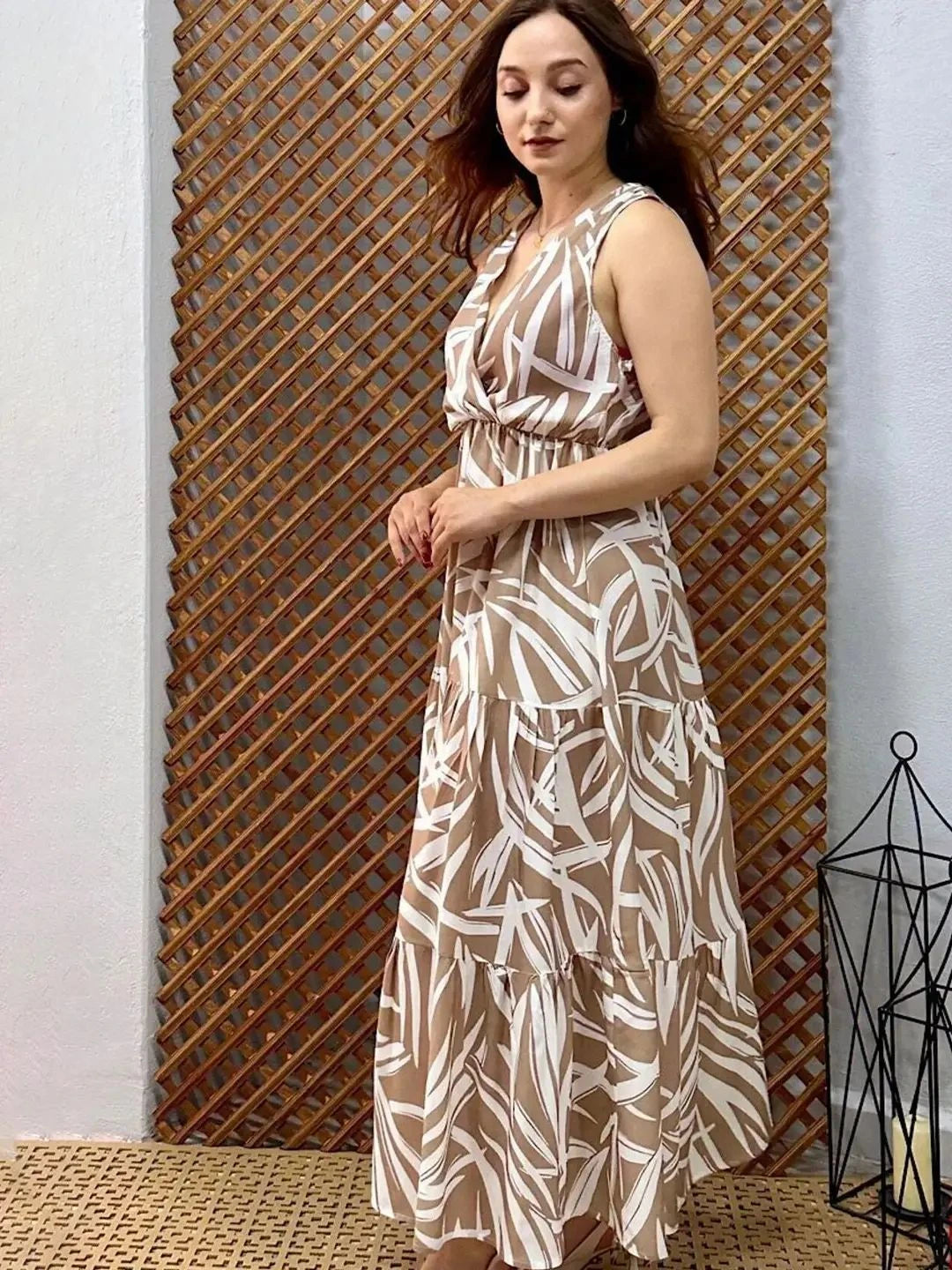 Woman wearing a beige and white patterned dress against a wooden lattice background