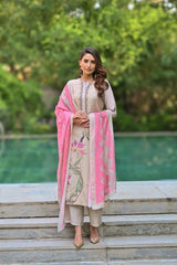 Woman in a traditional outfit with pink dupatta standing outdoors.