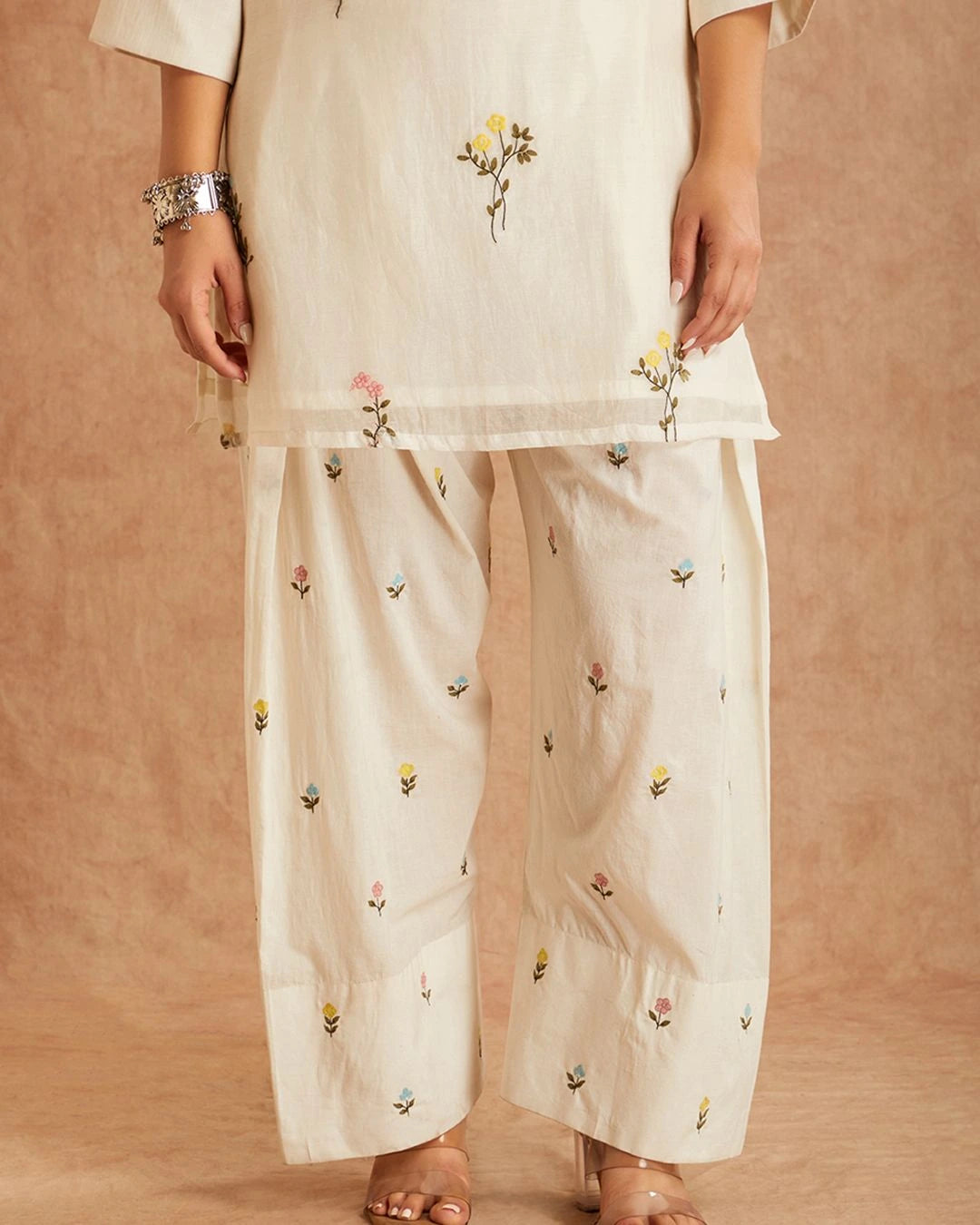 White outfit with floral embroidery on a beige background