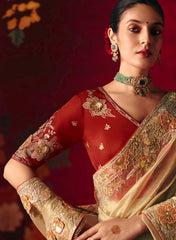 Woman wearing a traditional red and gold saree with intricate designs against a dark background