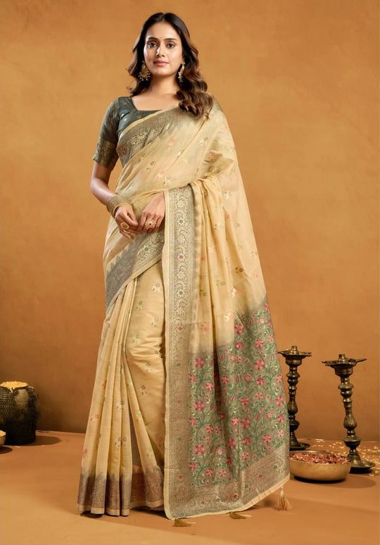 Woman wearing a beige saree with floral patterns on a brown background
