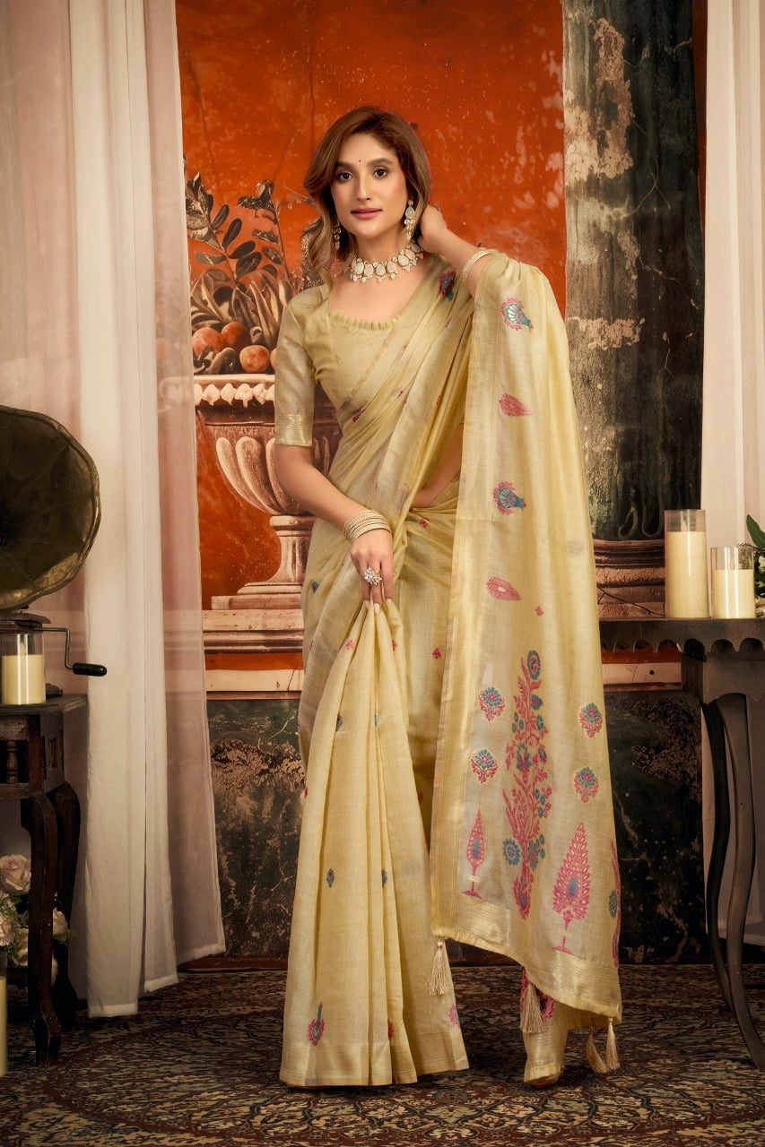 Woman in a traditional beige saree with floral patterns in an indoor setting.