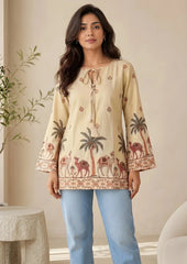 Woman wearing a beige embroidered top with palm tree and camel designs, standing indoors.
