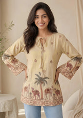 Woman wearing a beige blouse with camel and palm tree patterns in a home setting.
