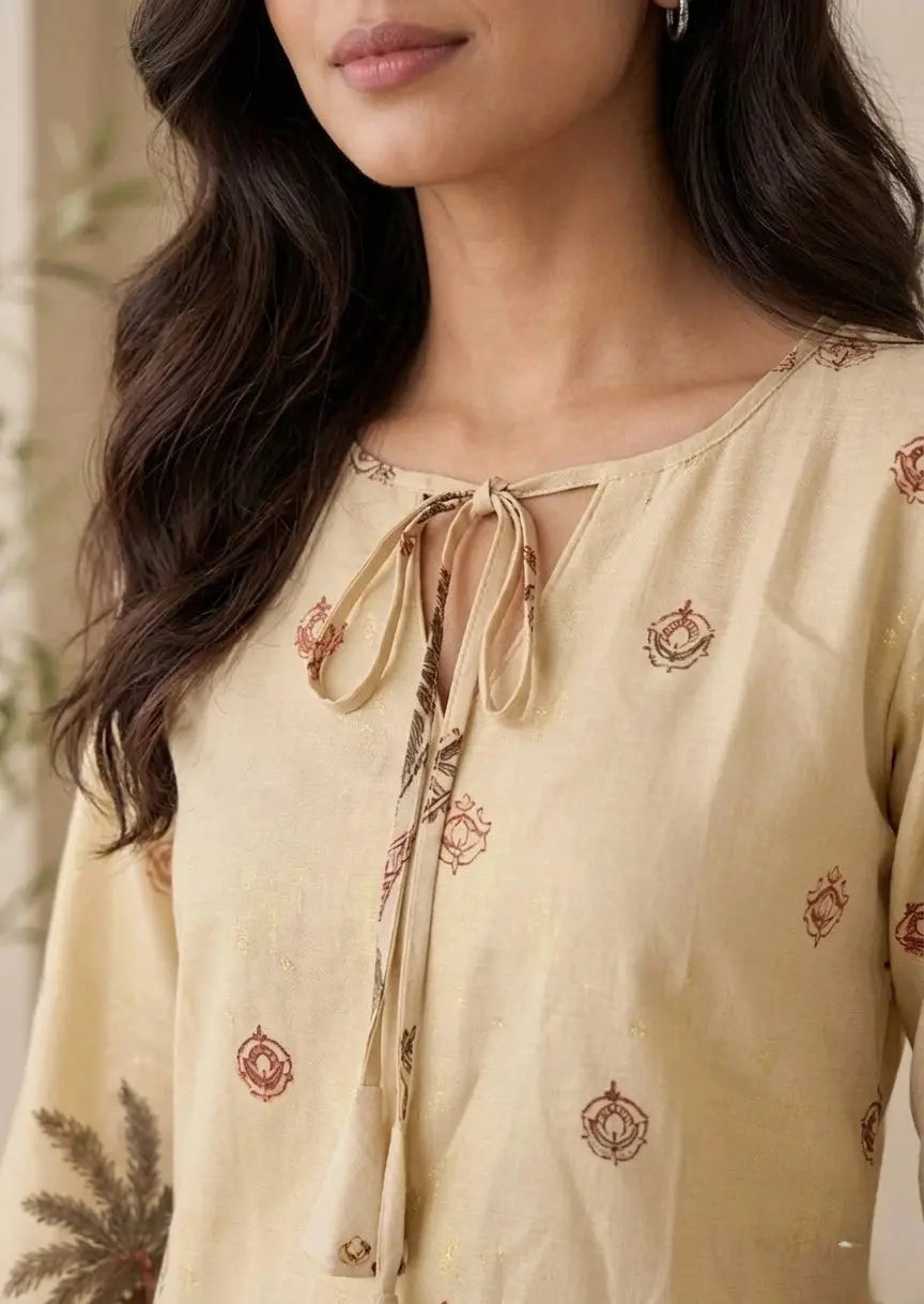 Woman wearing a beige embroidered top with a blurred background