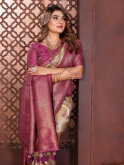 Woman in a traditional pink saree with gold patterns against an ornate wall.
