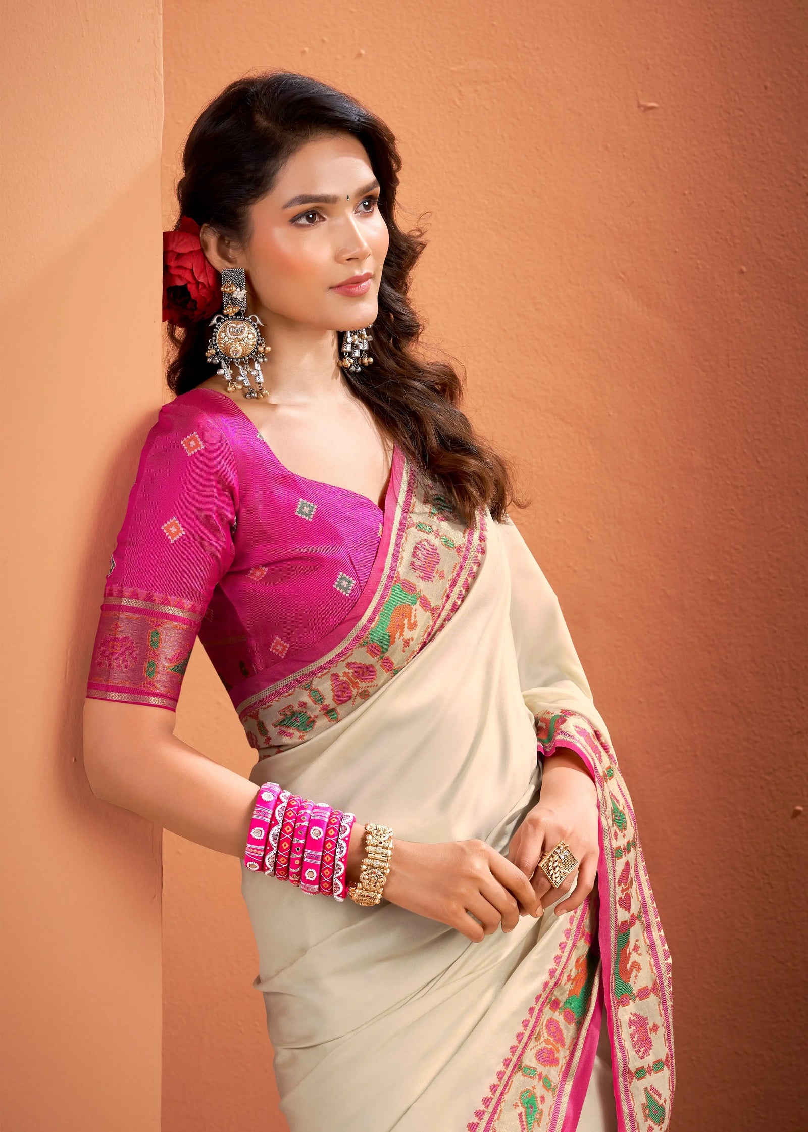 Woman wearing a traditional saree with a pink blouse against a beige background