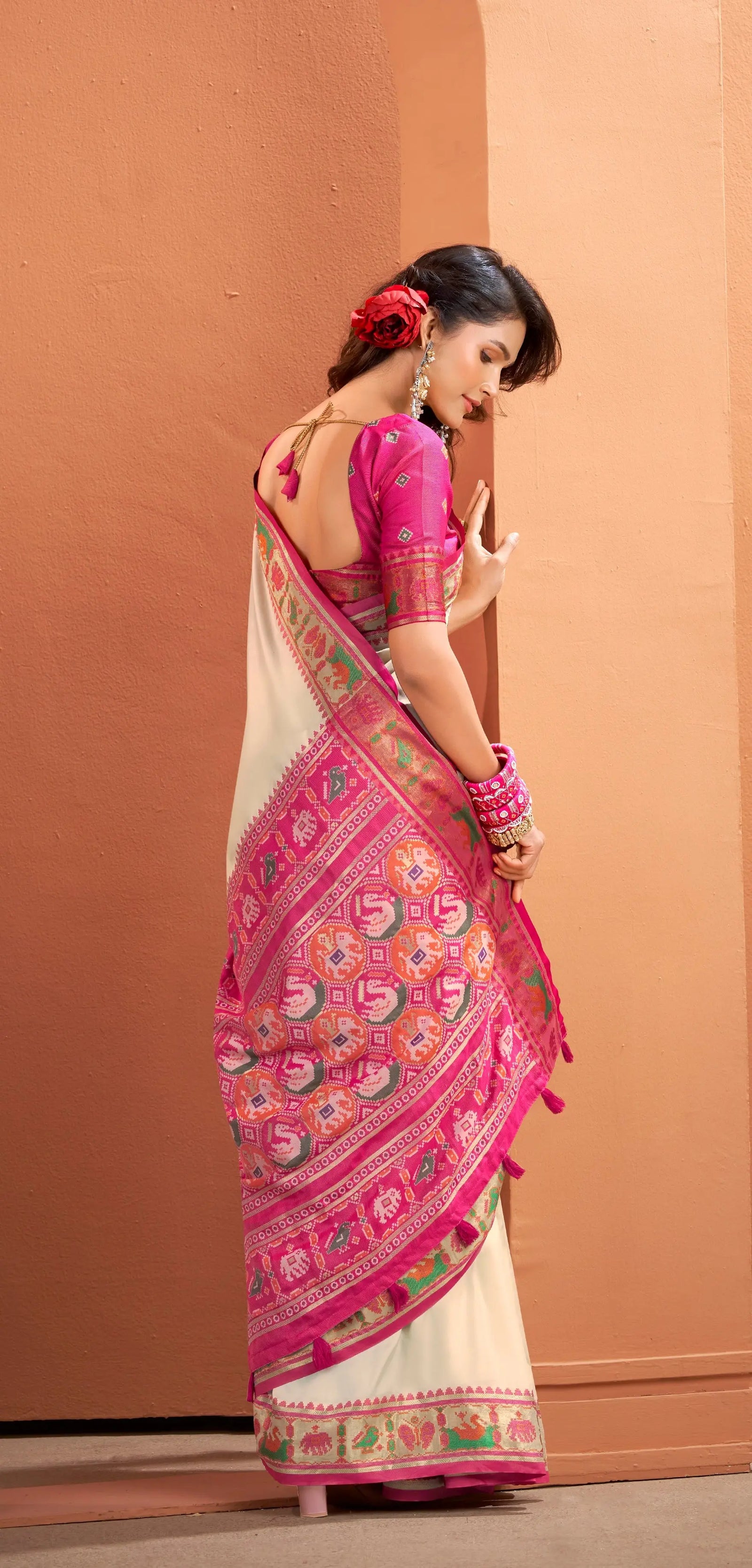 Woman wearing a pink and white saree with a floral pattern against a beige background