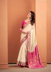 Woman wearing a traditional saree with pink and green patterns against a beige wall.