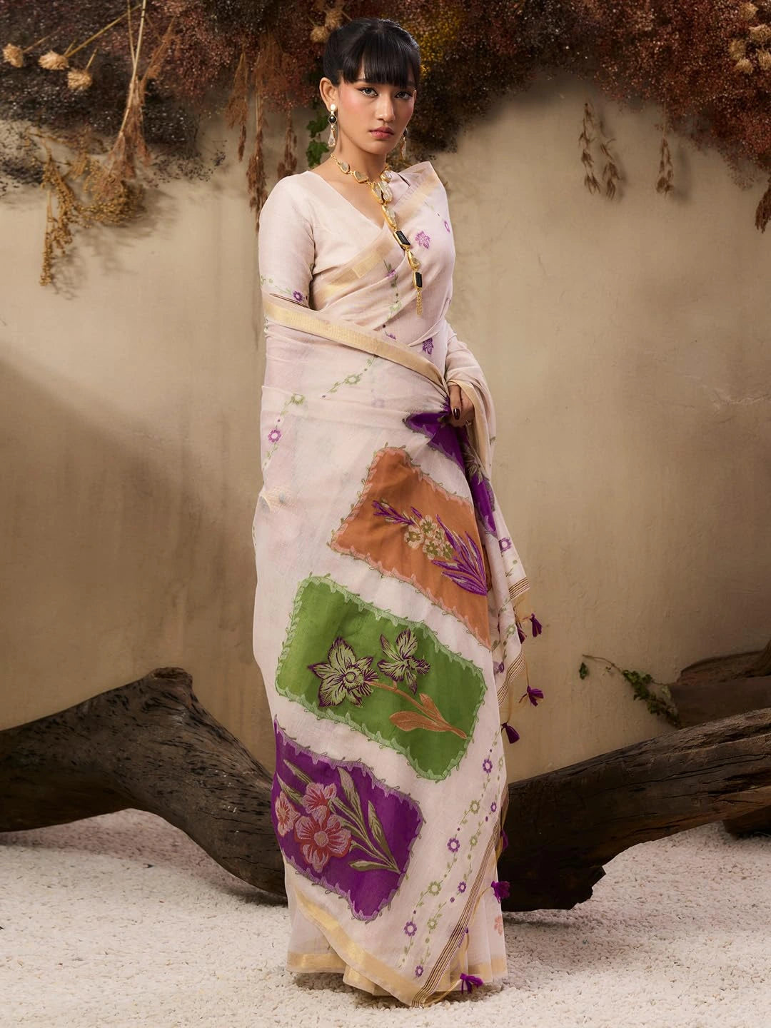 The saree features colorful patchwork-style floral panels in green, peach, and purple tones.