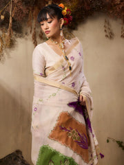 A woman stands elegantly in a soft pastel pink saree with delicate floral embroidery and printed motifs.