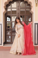 Woman in traditional attire with a red dupatta in front of an ornate door.