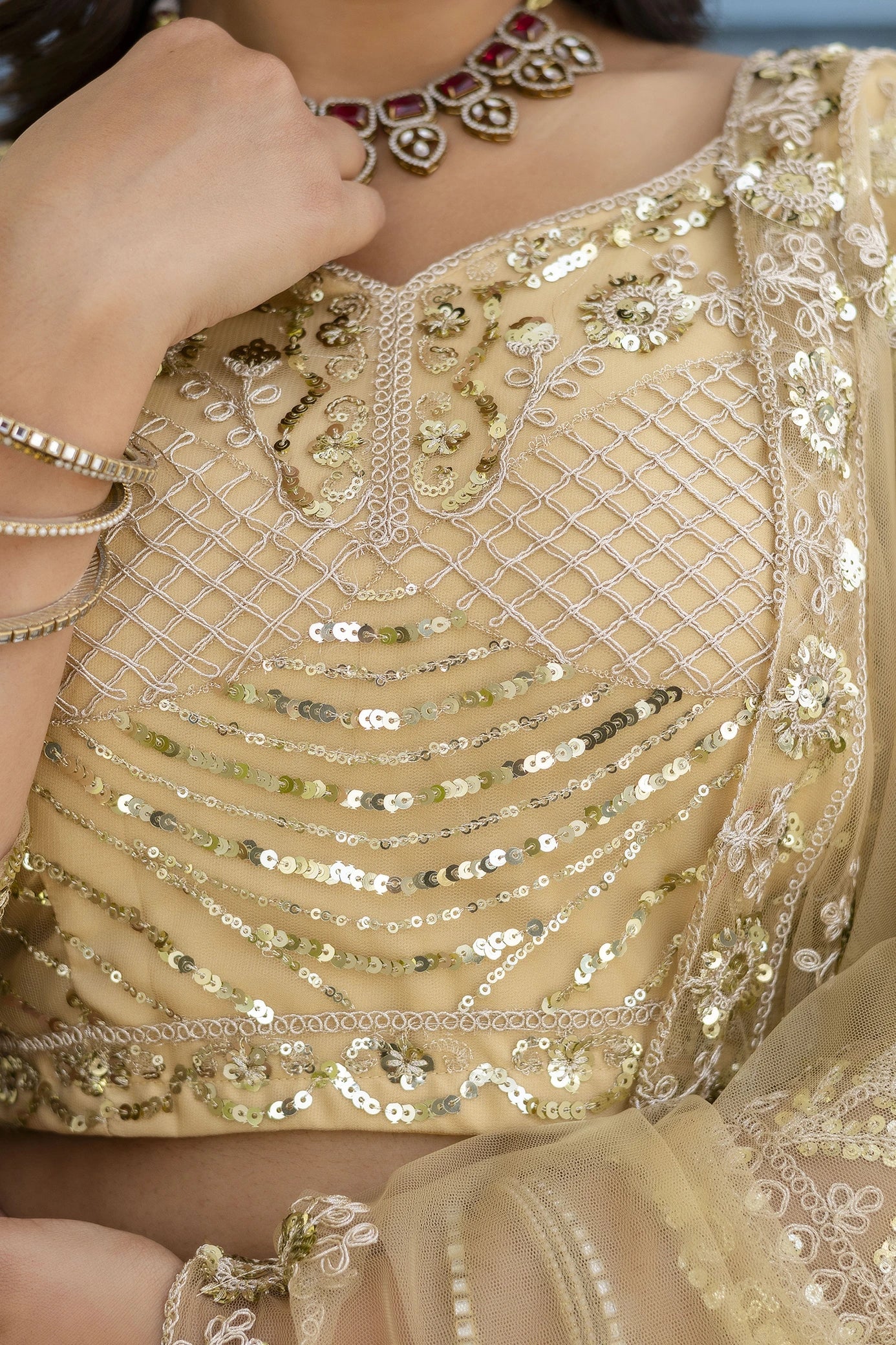 Close-up of a person wearing a gold embroidered saree with sequins.