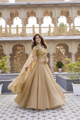 Woman in a gold traditional outfit standing in front of an ornate building.