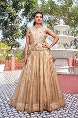 Woman in a gold traditional outfit standing outdoors with a fountain in the background