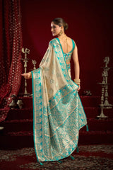 Woman in a teal and beige saree with a red background