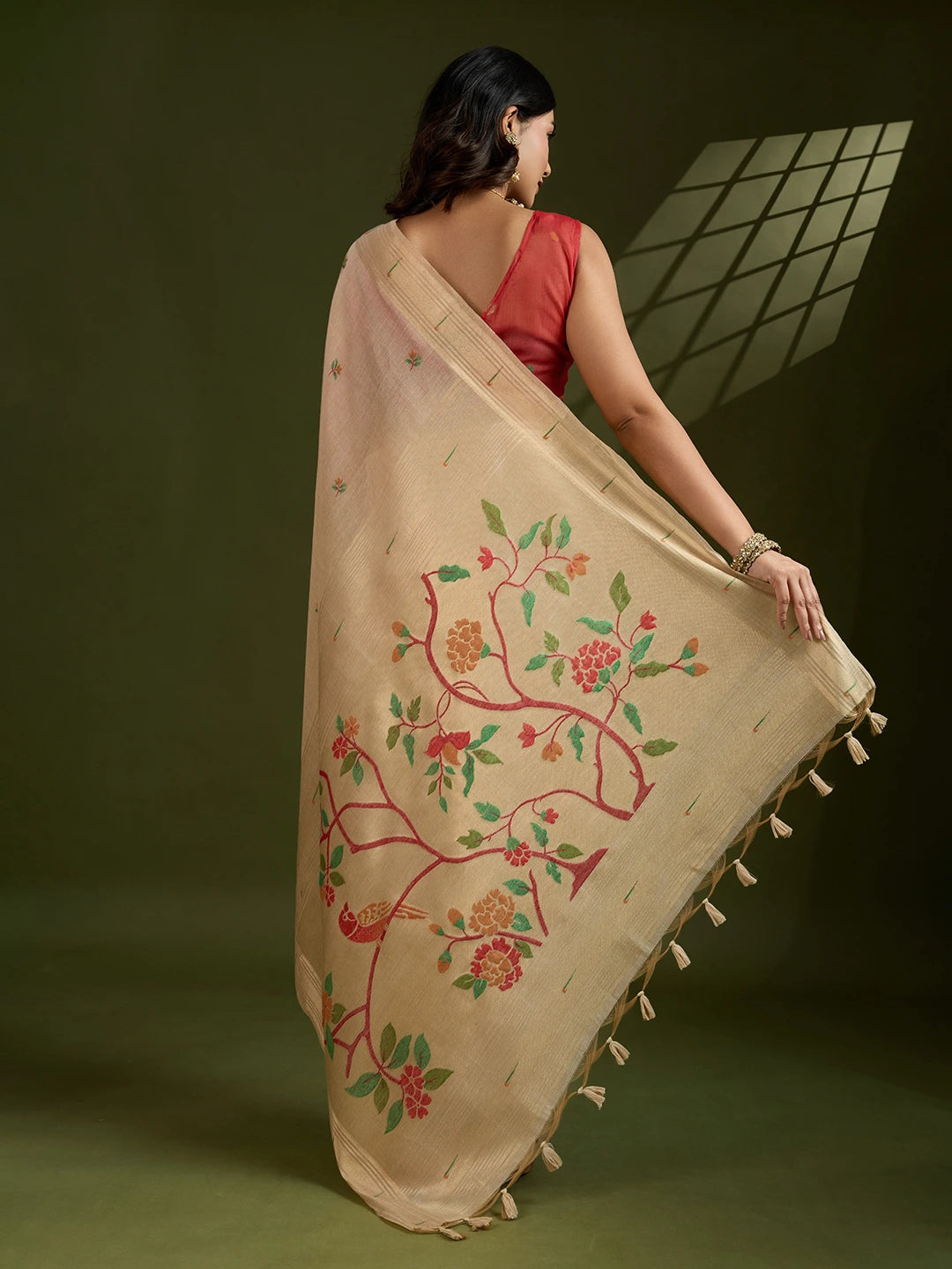Woman holding a beige embroidered fabric with floral patterns on a green background