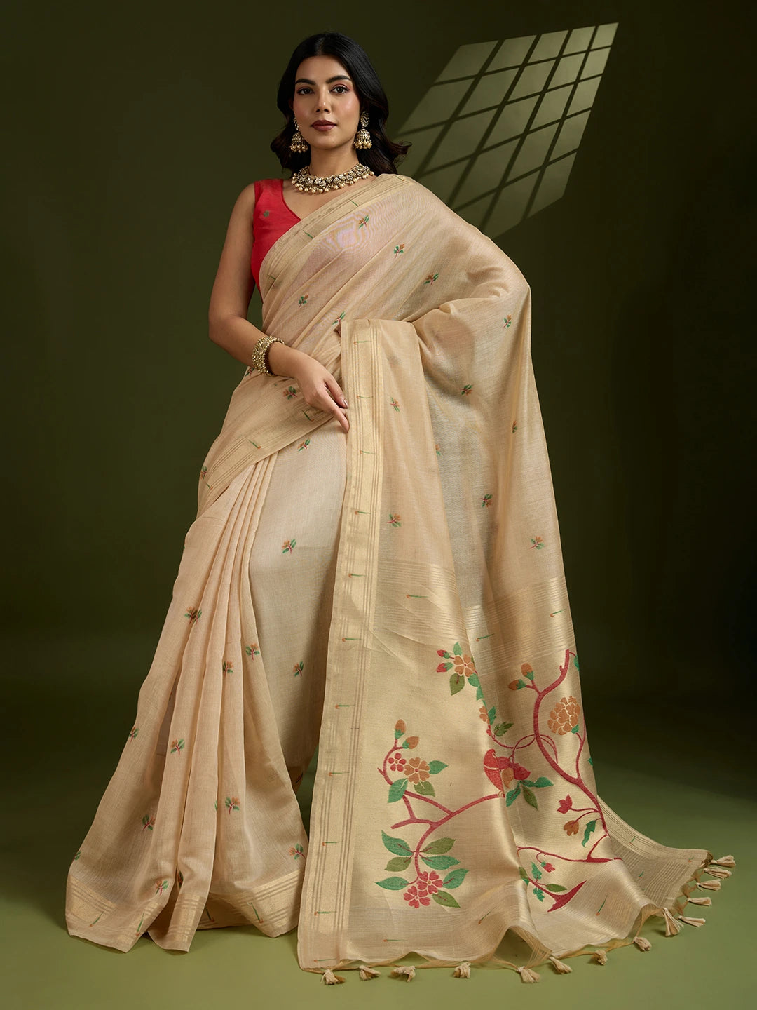 Woman wearing a beige saree with floral embroidery on a green background