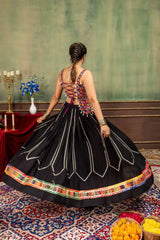 Back view of black lehenga showing open lace-up choli and circular skirt with white chevron embroidery