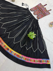 Flat lay detail of black circular lehenga skirt showing white chevron embroidery and colorful patola border