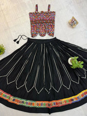 Flat lay of black heavy embroidered lehenga set with multicolor Kutchi choli and circular skirt