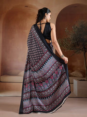 Woman wearing a black and white patterned saree in an indoor setting