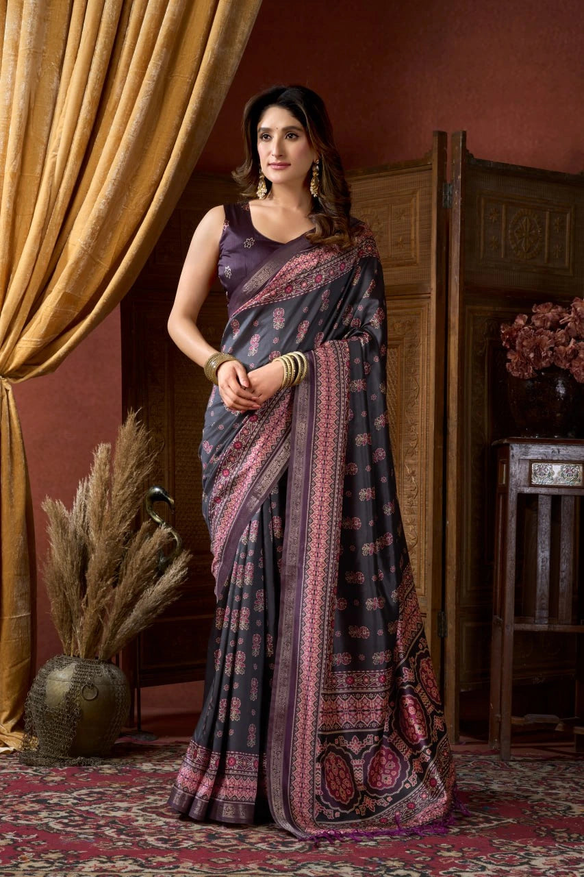 Woman in a patterned saree standing in an elegant room with decorative elements.