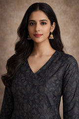 Woman wearing a dark patterned top against a brown background