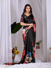 Woman wearing a black saree with floral patterns against a white curtain background