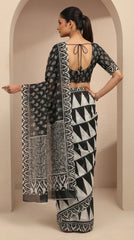 Woman wearing a black and white patterned saree with a matching blouse in a neutral setting.
