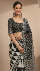Woman wearing a black and white patterned saree against a beige background