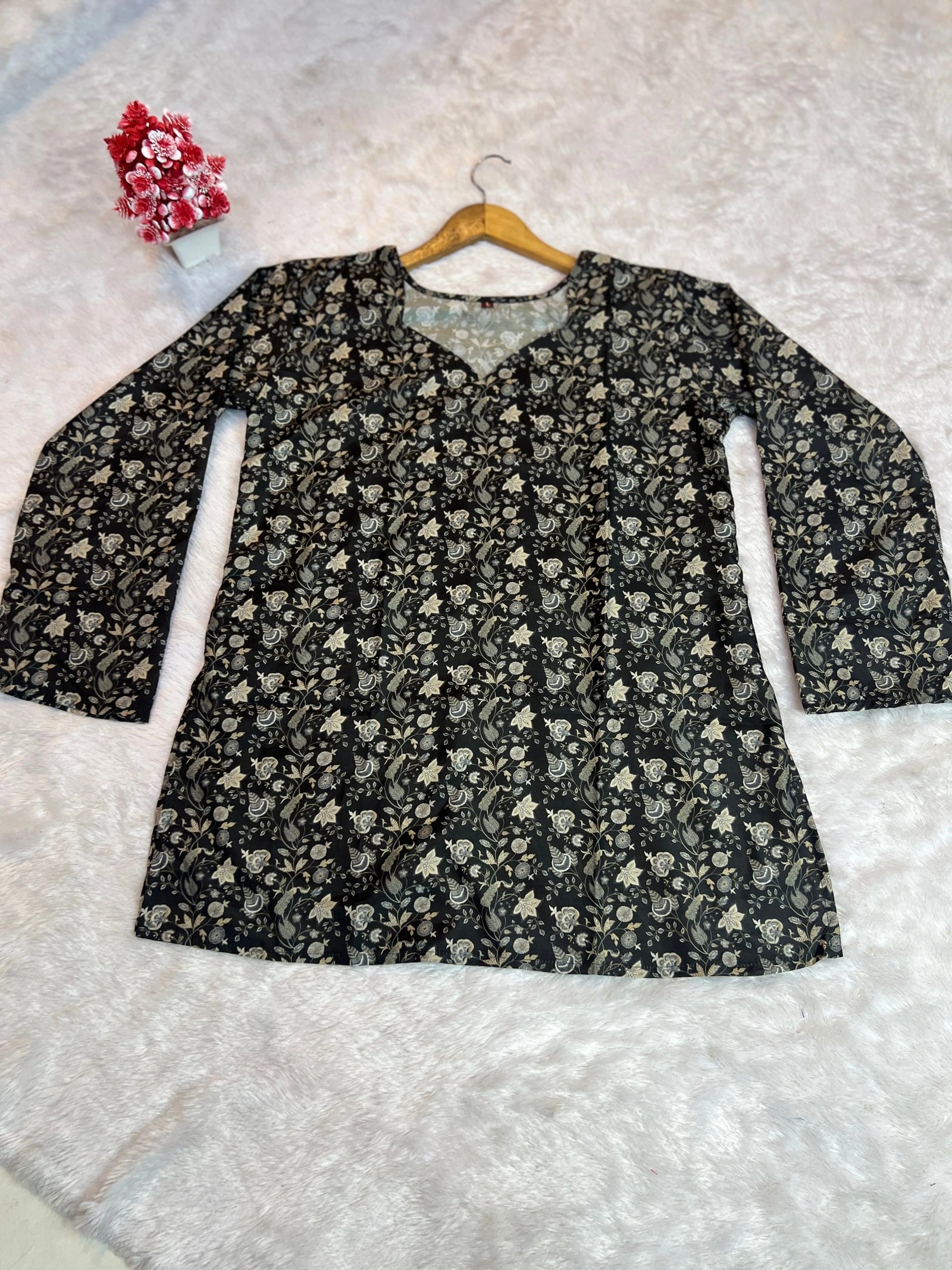 Floral-patterned top on a hanger against a textured white background