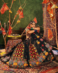 Woman in traditional attire sitting in a decorated room with colorful decorations and patterns.