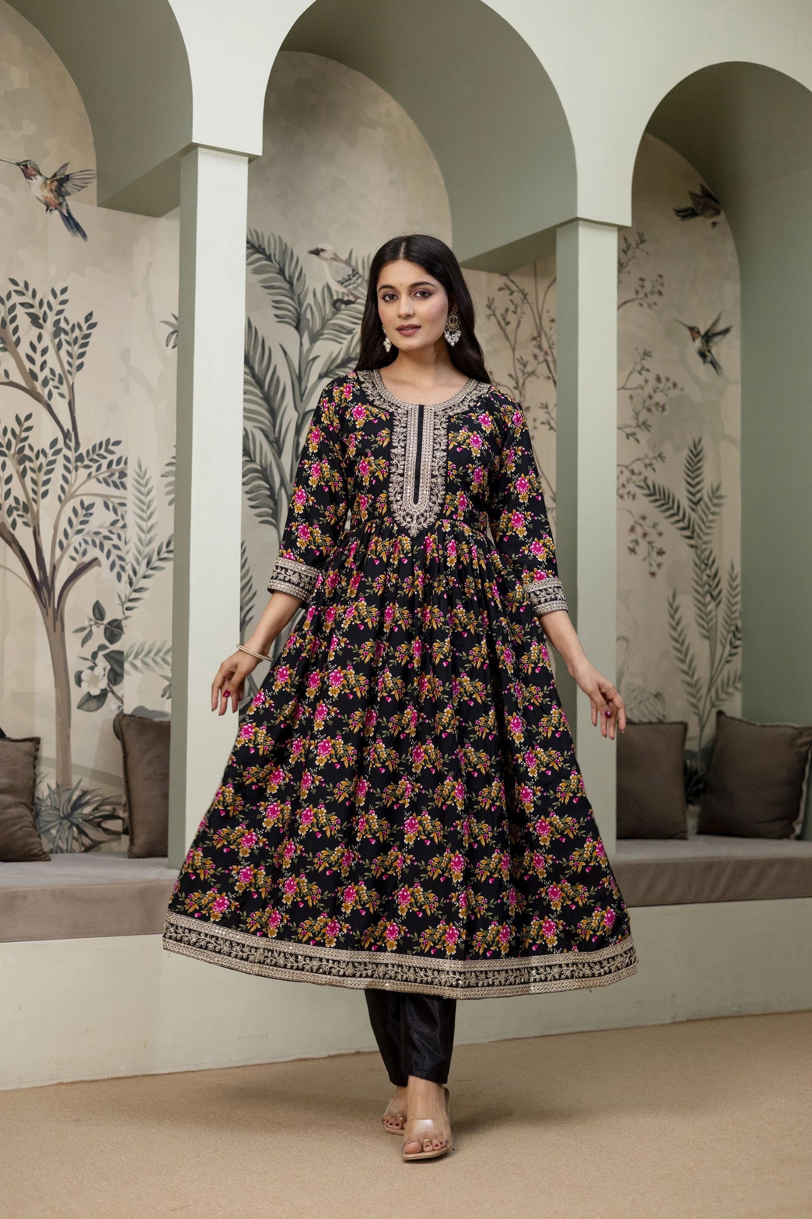 Woman wearing a floral dress in an indoor setting with decorative walls.