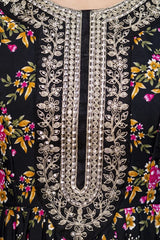 Close-up of a black garment with floral patterns and intricate silver embroidery.