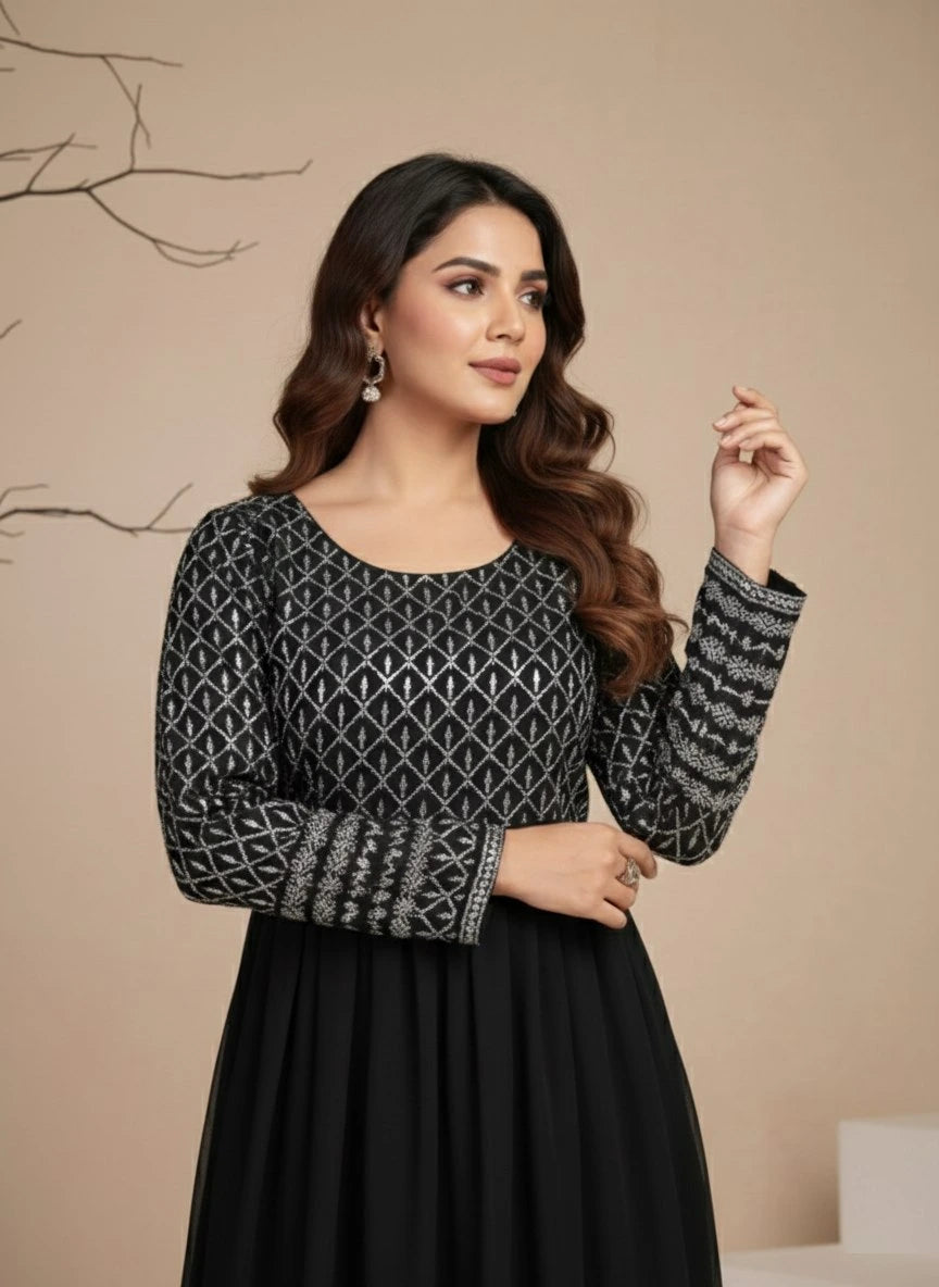 Woman wearing a black and silver patterned top with a plain background