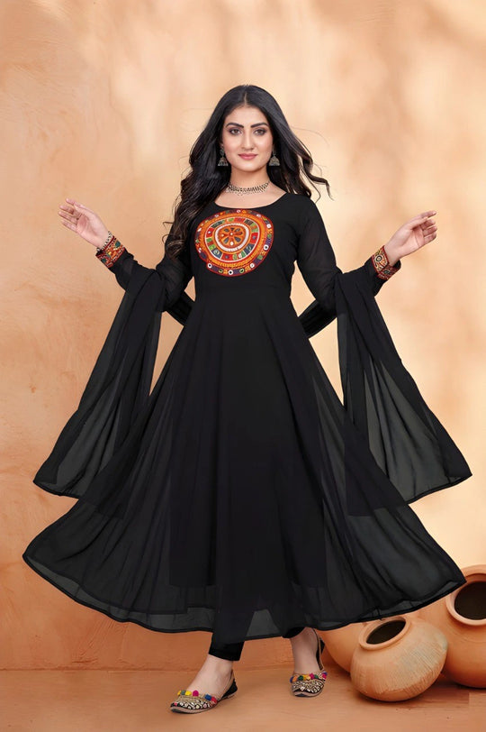 Woman wearing a black dress with colorful embroidery against a beige background