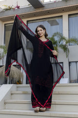 Woman holding a black and red saree in front of a building