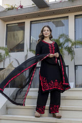 Woman in black and red traditional outfit standing on steps with a modern building in the background