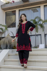 Woman in a black and red traditional outfit standing on steps outside a modern building.