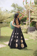 Eye-catching golden circular foil patterns add a bold and fashionable touch to the flowing black skirt.